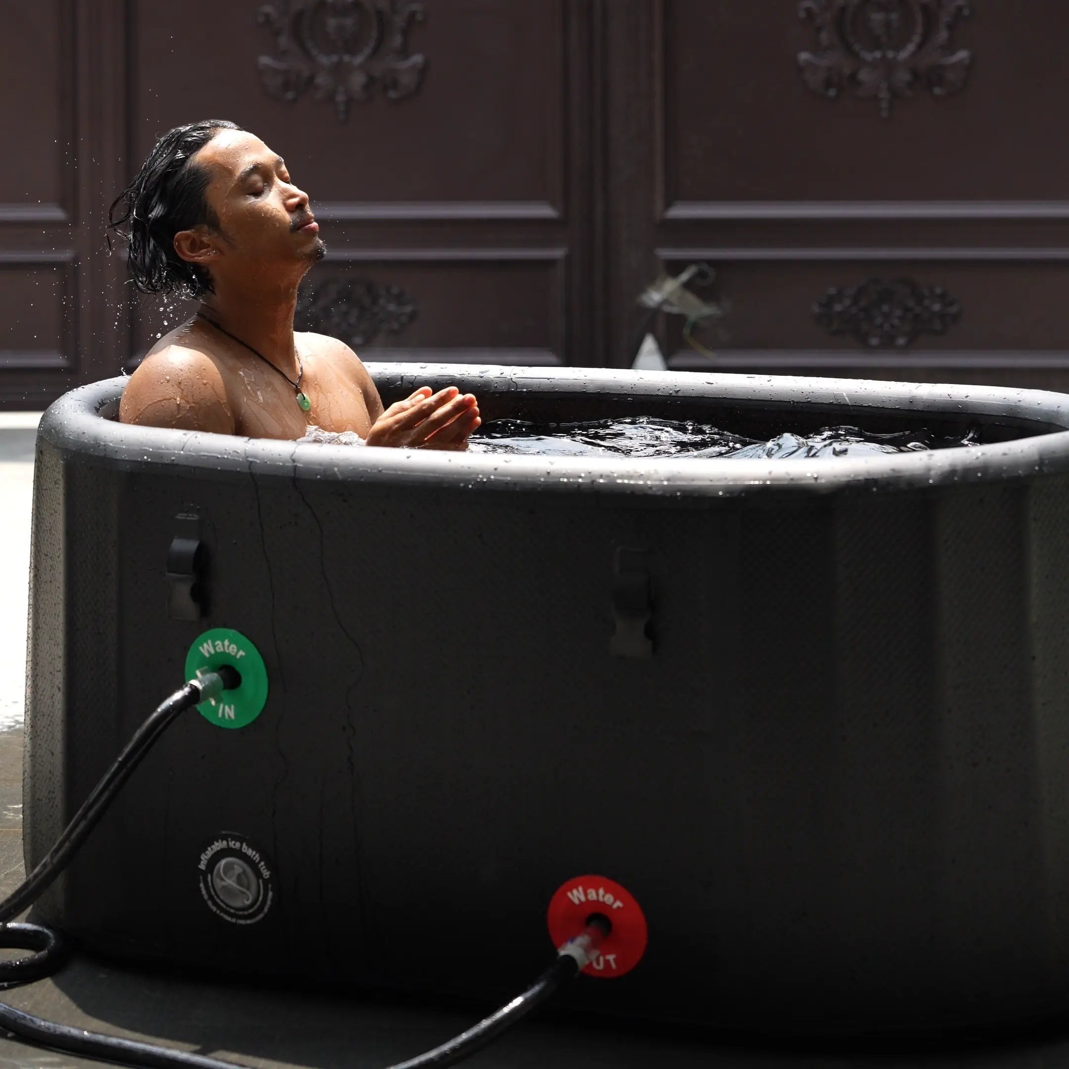 A man using a Garvnive black PVC ice bath tub for cold therapy recovery; the tub features an air-layered insulation design.