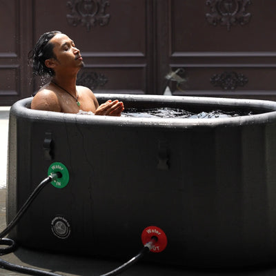 A man using a Garvnive black PVC ice bath tub for cold therapy recovery; the tub features an air-layered insulation design.
