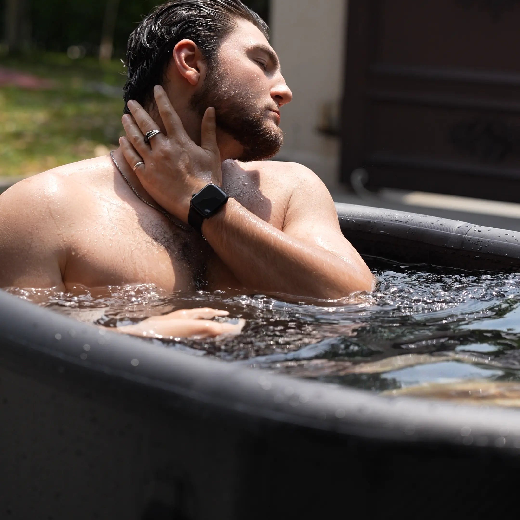 A man using a Garvnive black PVC ice bath tub for cold therapy recovery; the tub features an air-layered insulation design.